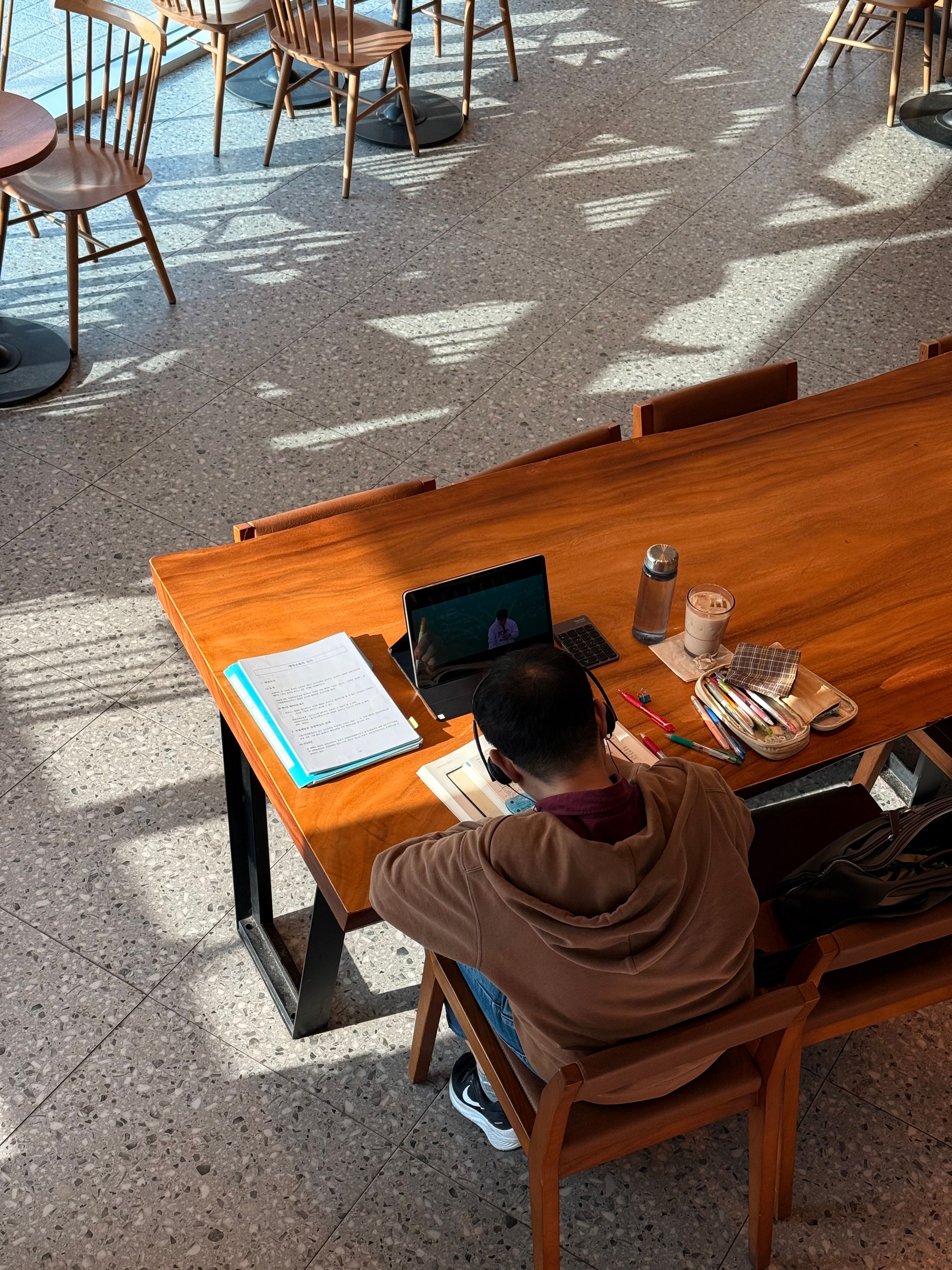 A student studies with a laptop and books in a modern cafe