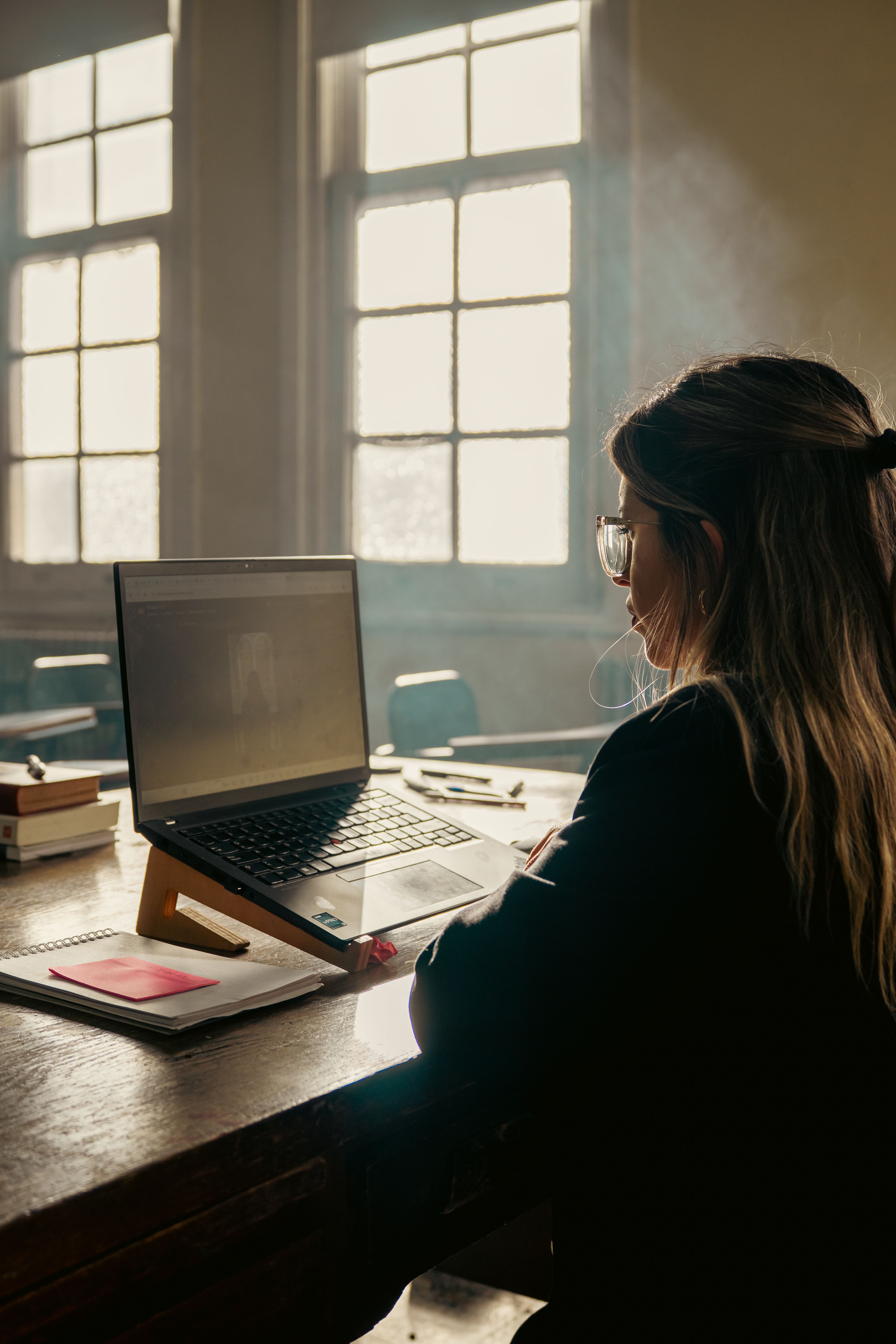 A student studies with a laptop in a sunny classroom