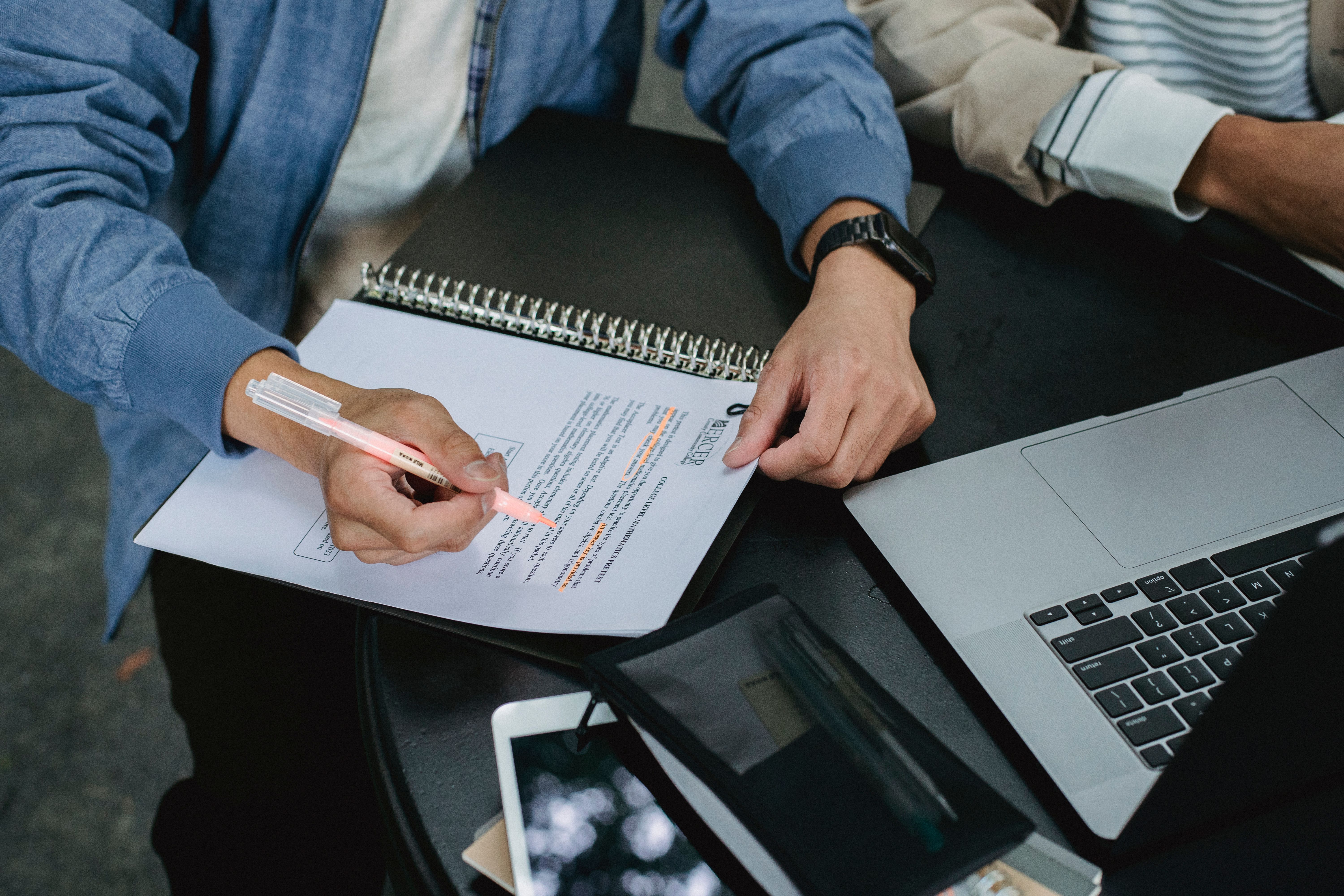 Students annotate a document beside a laptop